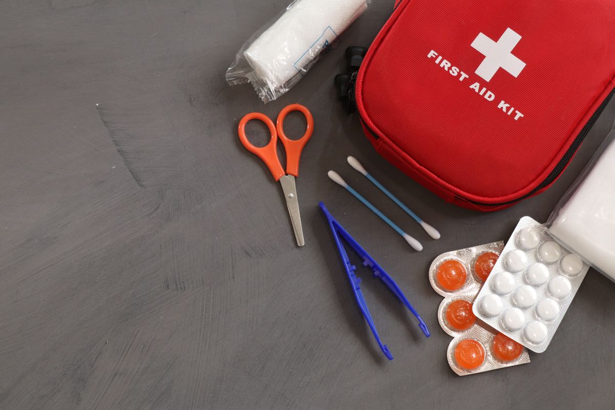 Kit de primeiros socorros aberto com bandagens e medicamentos, representando acidente em viagem a trabalho