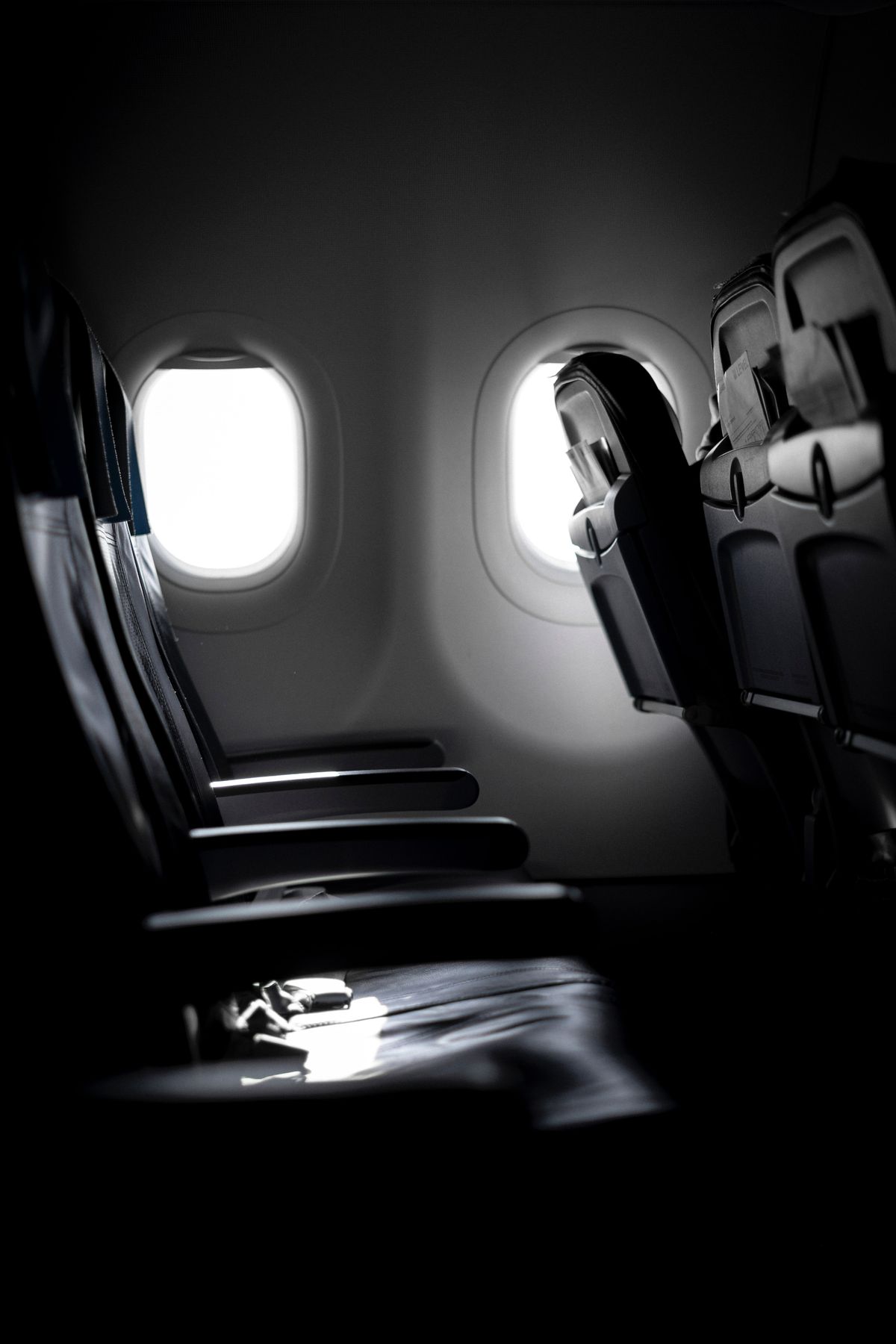 Poltronas vazias na cabine de um avião, junto às janelas, representando os bilhetes não voados