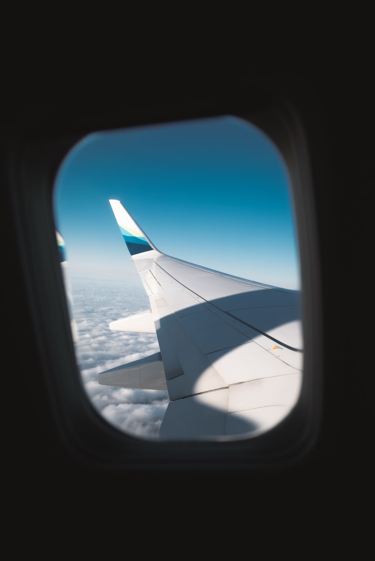 Vista da asa do aviao pela janela acima das nuvens, representando as milhas acumuladas em viagem a trabalho