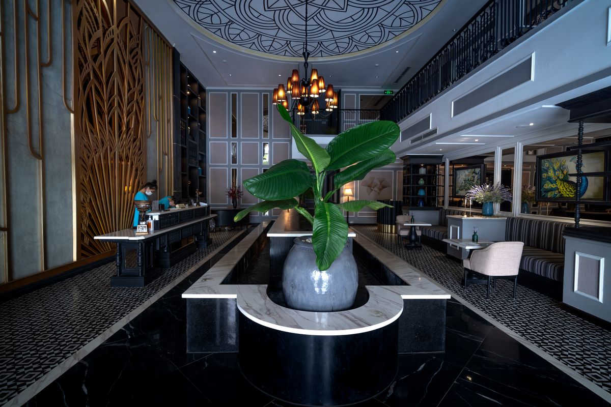 Lobby de hotel com recepcao, lustre e poltronas, representando a politica de hospedagem corporativa