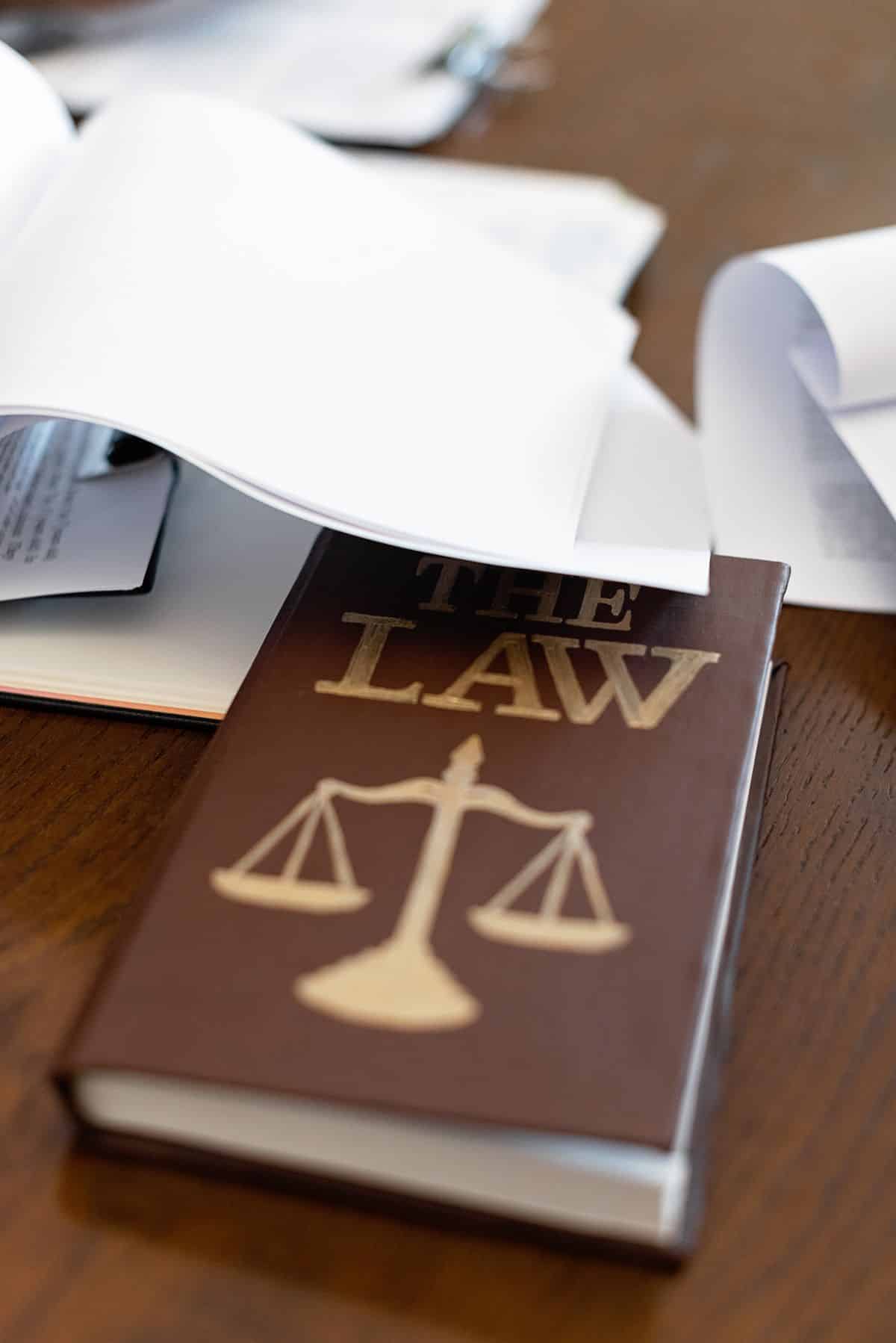Livro de leis sobre mesa de madeira ao lado de documentos, representando a reforma tributaria aplicada as despesas de viagem