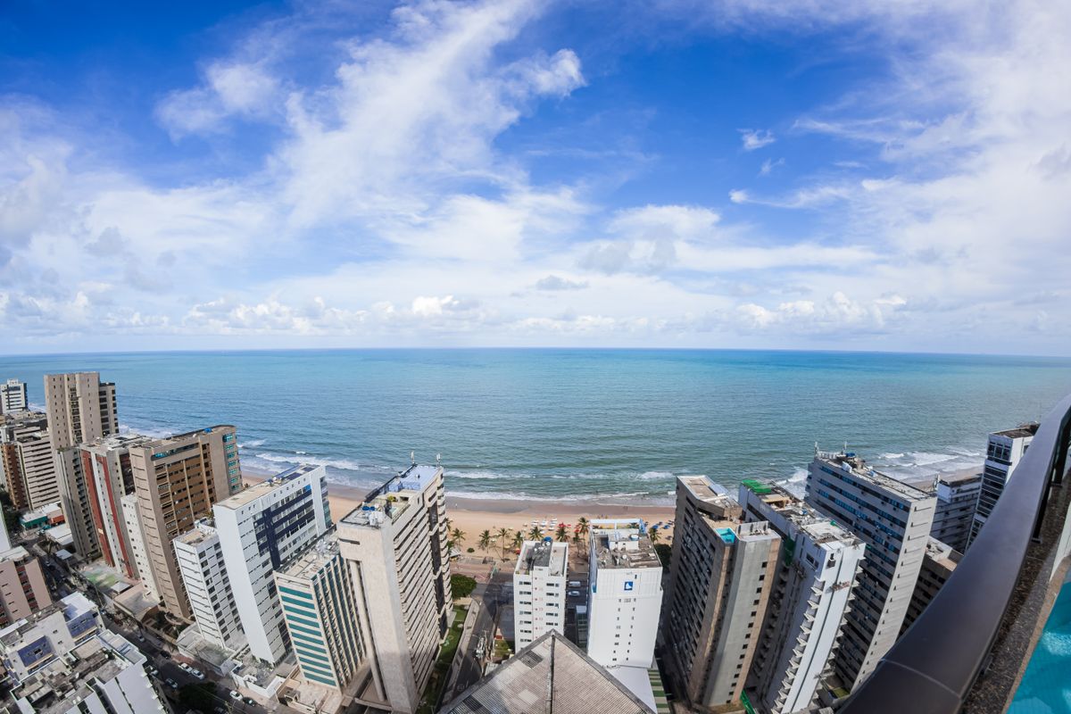 Vista aerea da orla de Recife com predios e praia, representando o turismo de negocios no Nordeste