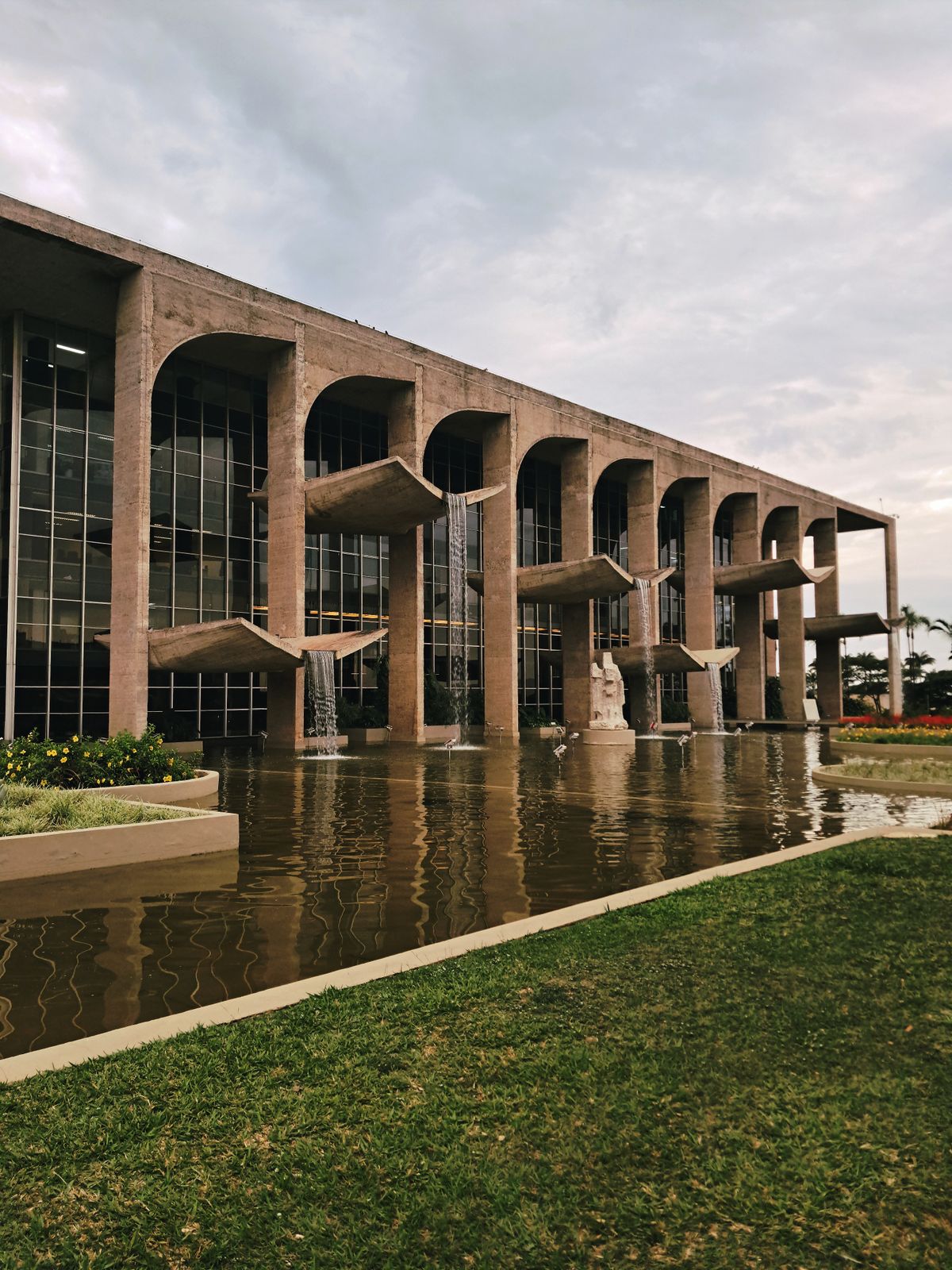 Fachada em arcos do Palácio da Justiça, em Brasília, com espelho d'água e cascatas, representando as viagens corporativas no setor público