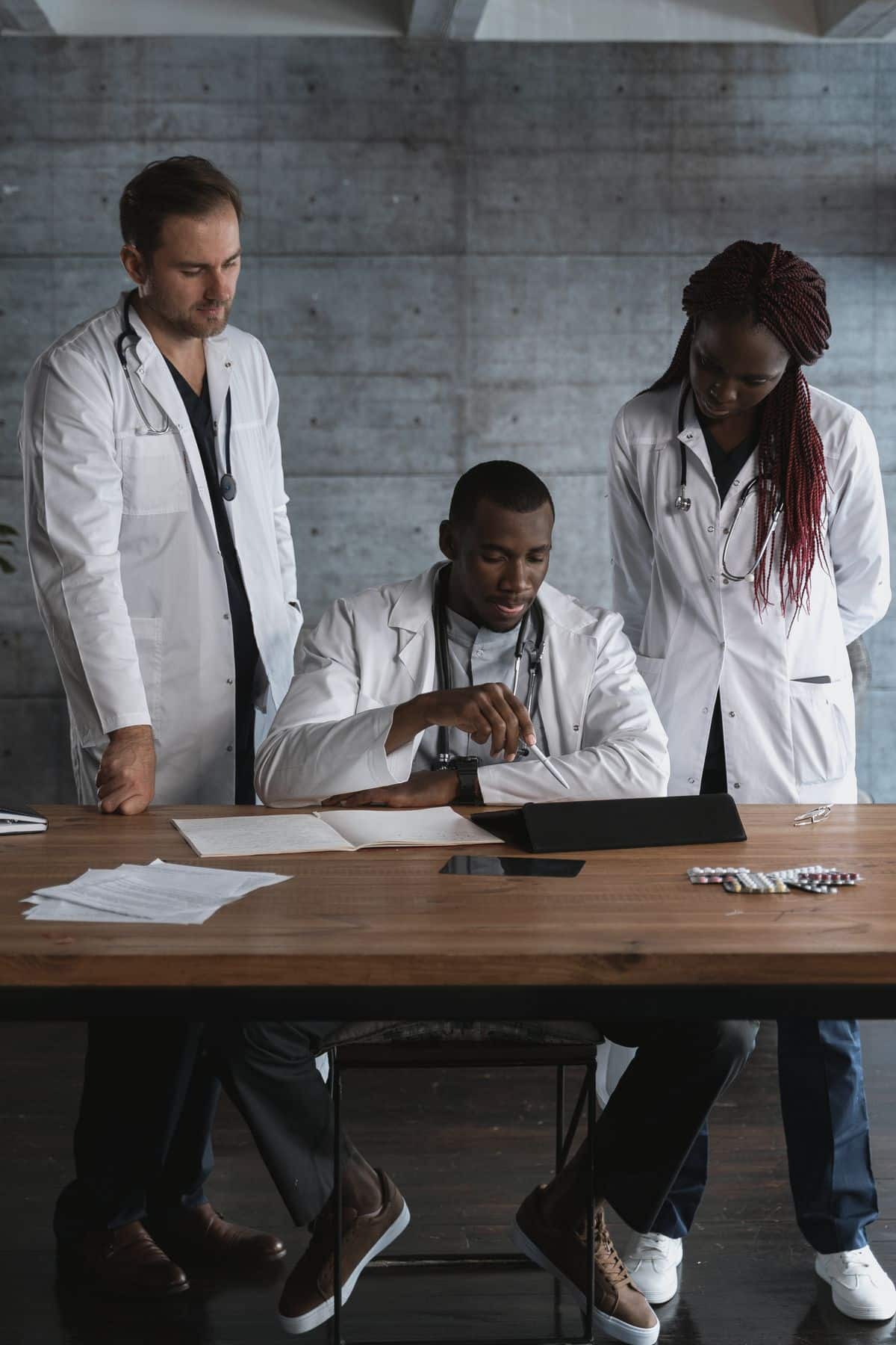 Tres medicos de jaleco analisando documentos sobre a mesa, representando viagens corporativas na saude e farma